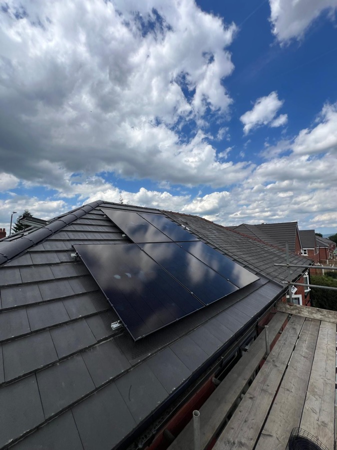 Solar panels installed on a pitched tile roof under a blue sky