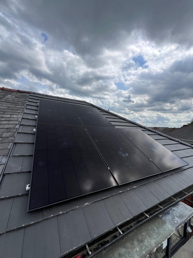 Solar panel installation on a roof under a cloudy sky